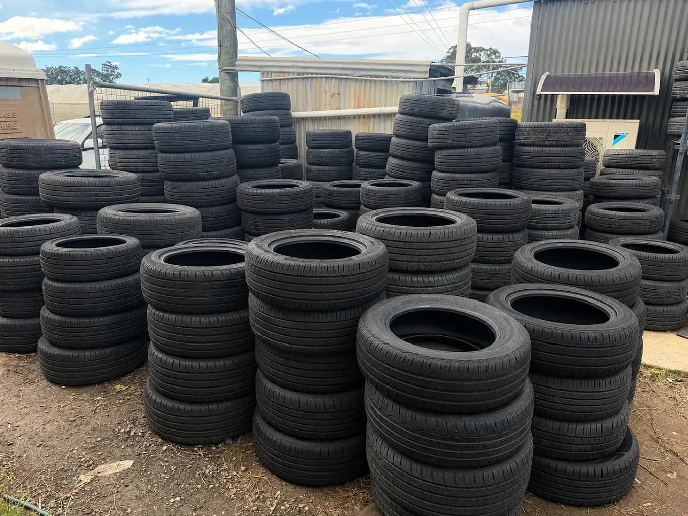 Stacks of used tyres on the racks in the yard at Auswide Tyres, Austral